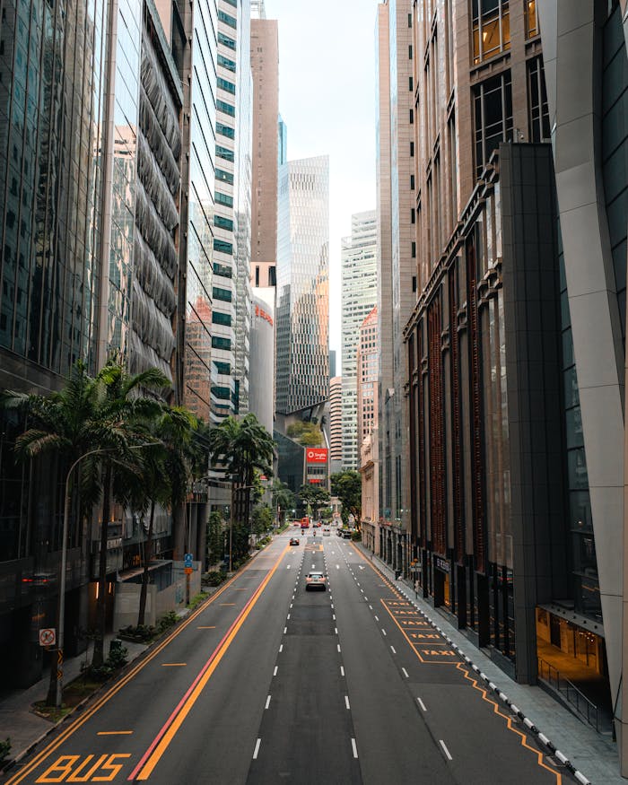 A view of Singapore's central business district with towering skyscrapers and an empty street.