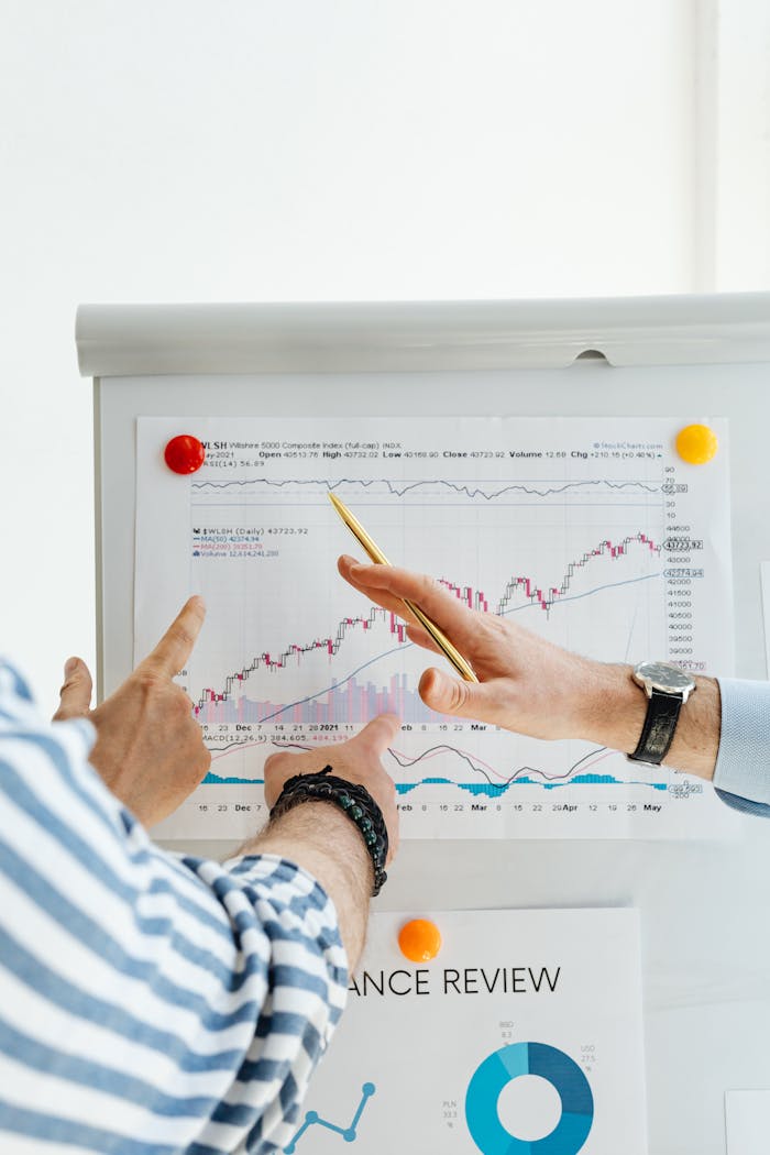 About Two people analyzing financial charts on a whiteboard during a business meeting.